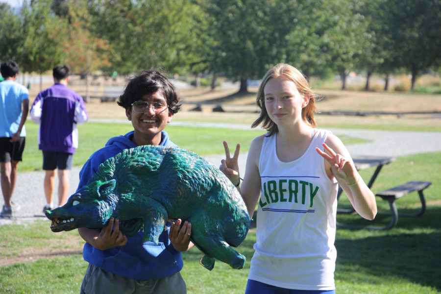 Posing for the camera: Sophomores Akash Krishna and Scarlett Saam smile while holding up the mascot Boaris. 